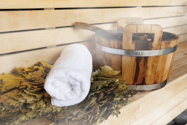 Bucket, ladle, broom and white towel in a sauna. Classic sauna accessories